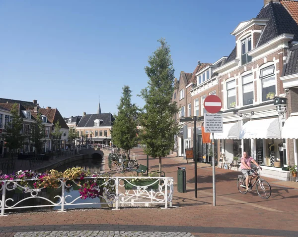 Hombre en bicicleta cerca del antiguo canal en el centro de dokkum en holandés provisiones — Foto de Stock