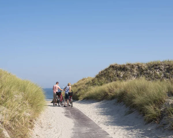 Paar met fietsen op de top van de duinen in de buurt van zee op het Duitse eiland o — Stockfoto