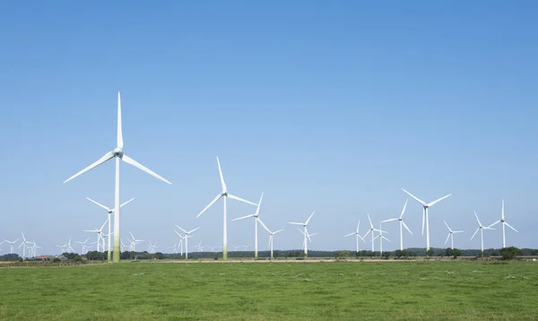 Vindkraftverk i landsbygdslandskap i Ostfriesland i norra Tyskland och blå himmel — Stockfoto