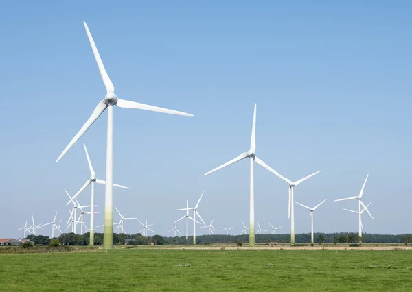 Windräder in der ländlichen Landschaft Ostfrieslands im Norden Deutschlands und blauer Himmel — Stockfoto