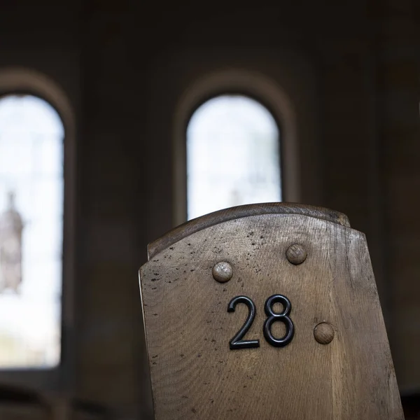 Número 28 no lado do velho banco de igreja de madeira com janelas romanas — Fotografia de Stock