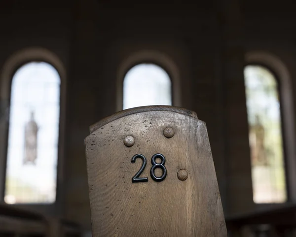 Número 28 no lado do velho banco de igreja de madeira com janelas romanas — Fotografia de Stock