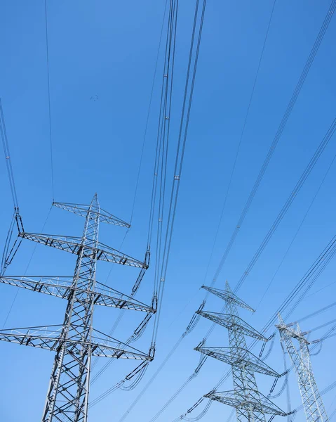 Postes de energia e fios de eletricidade contra o céu azul — Fotografia de Stock