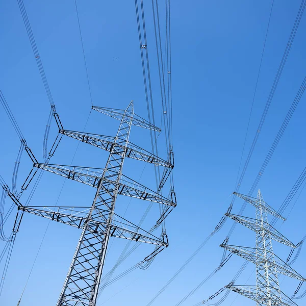 Pylony mocy i przewody elektryczne przed błękitnym niebem — Zdjęcie stockowe