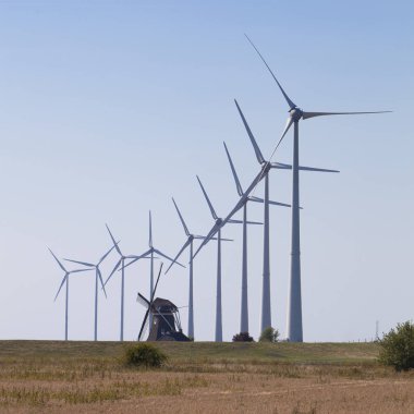 mavi gökyüzüne karşı eski Hollanda yel değirmeni ve modern rüzgar türbinleri 