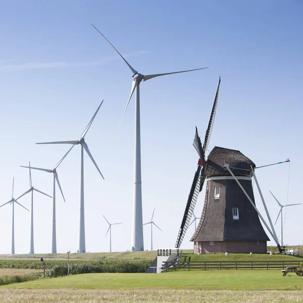 Molino de viento holandés viejo y modernas turbinas de viento contra el cielo azul en — Foto de Stock