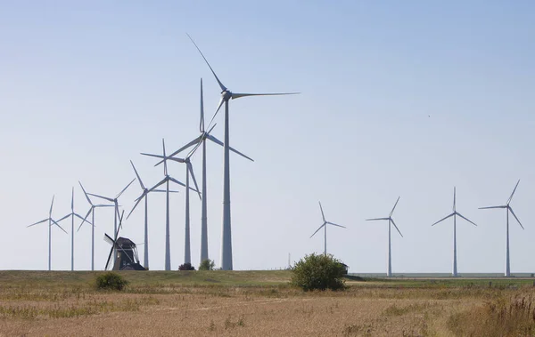 Alte holländische Windmühle und moderne Windräder vor blauem Himmel in — Stockfoto