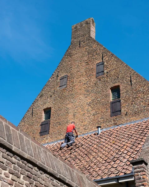 Hombre de camisa roja repara edificio medieval en viejo centro de zutphen en los Países Bajos — Foto de Stock