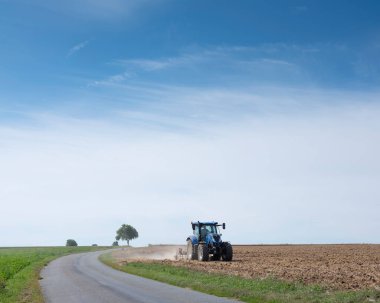 Fransa 'nın kuzeyinde Harrow tarlasında traktördeki çiftçi