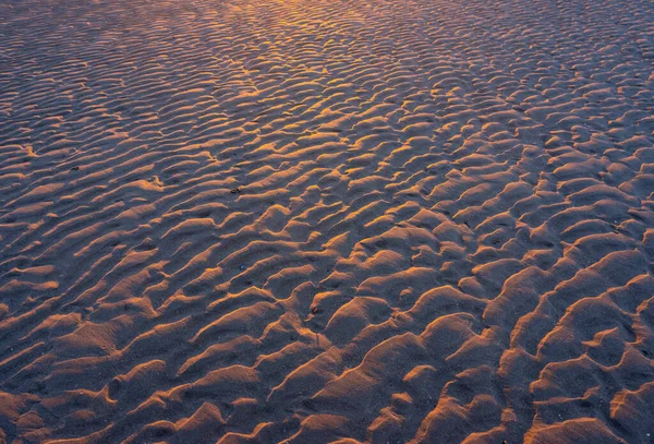 Песчаные рябь на пляже в теплом свете заходящего солнца — стоковое фото