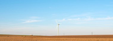 Fransa 'nın kuzeyinde hasat sonrası tarlalarda arka planda rüzgar türbinleri var.