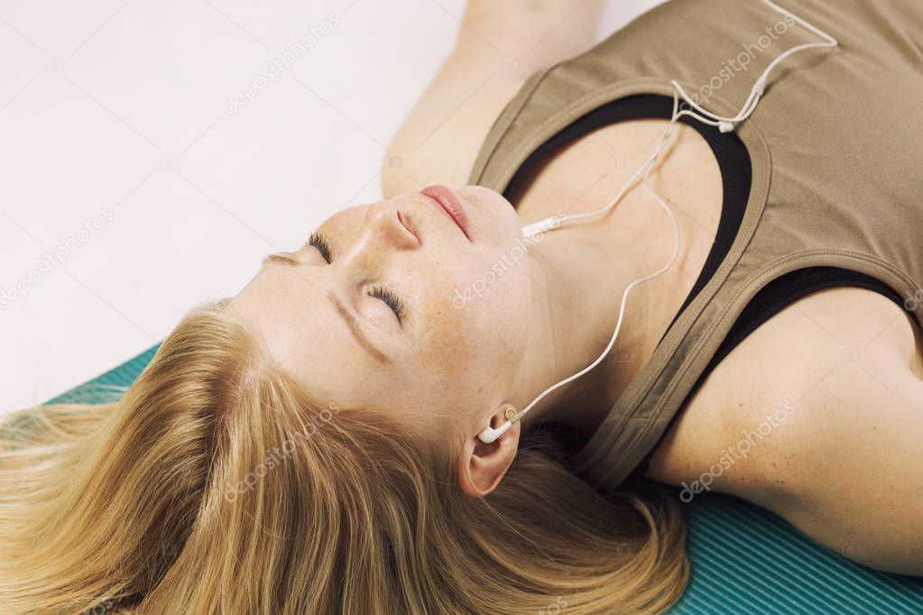 Beautiful young woman on a yoga mat relaxes, close-up