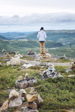 Bir adam güzel bir manzara taşlar arasında bir tepe üzerinde duruyor