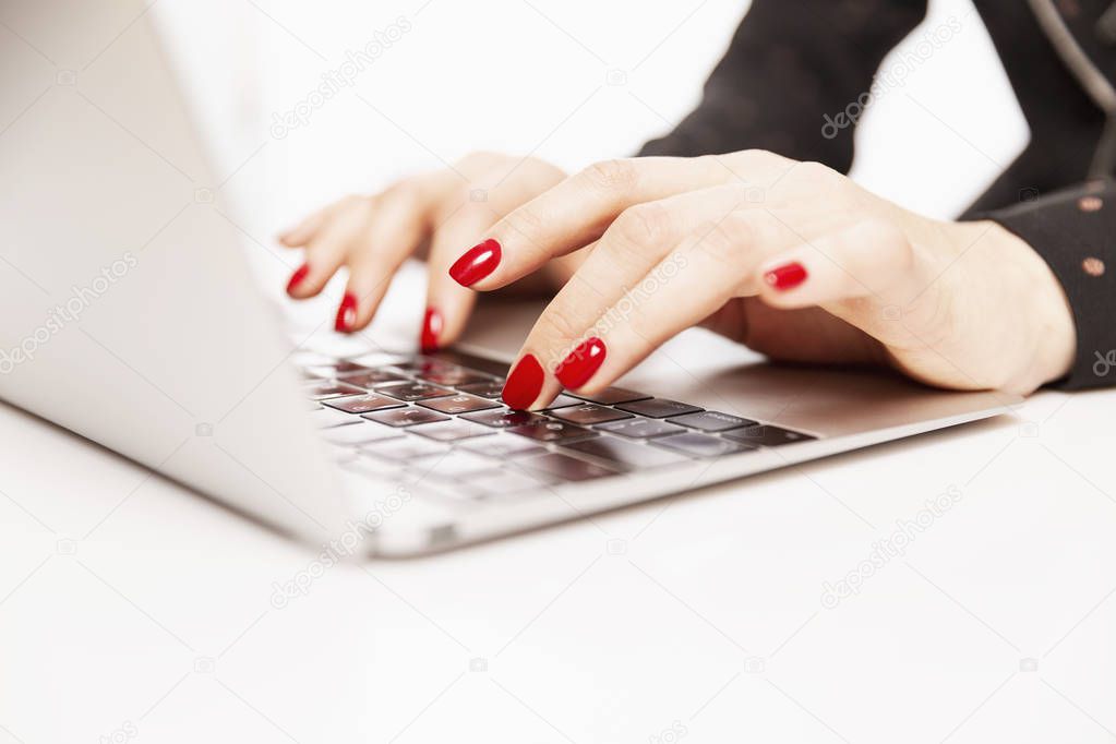 Women's hands with a beautiful bright manicure on the keyboard of a stylish laptop, close-up