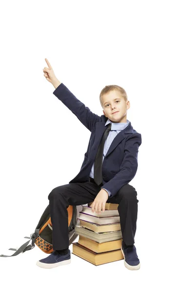 Schattig schooljongen zittend op boeken en duim opdagen, geïsoleerd op witte achtergrond — Stockfoto