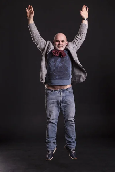 Elegante anciano hombre de pelo gris en un salto, de longitud completa, fondo negro — Foto de Stock