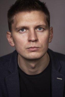 Şirin ciddi genç adam bir ceket, gri arka planda