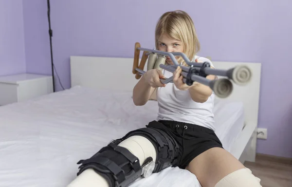 Mujer después de una operación en su pierna está sentado en la cama . — Foto de Stock