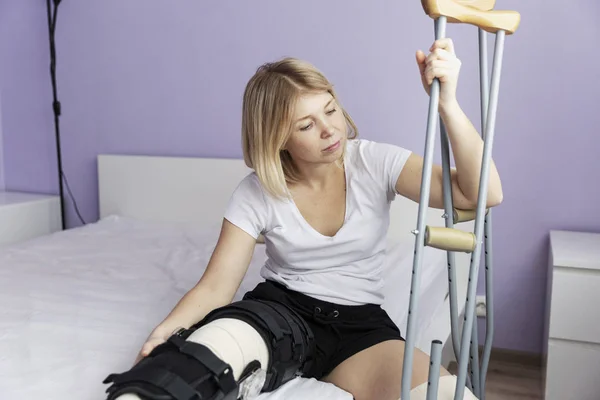 Mujer triste después de una operación en su pierna está sentado en la cama . —  Fotos de Stock