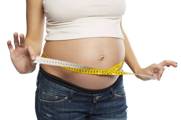 En gravid kvinna mäter bukens omkrets. Isolerad på en vit bakgrund. — Stockfoto