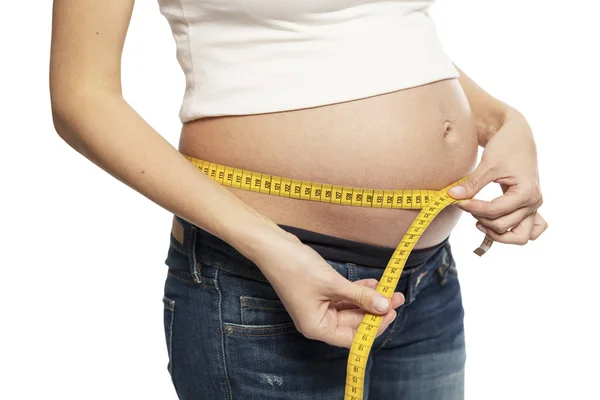 Una donna incinta misura la circonferenza addominale. Isolato su sfondo bianco. — Foto Stock