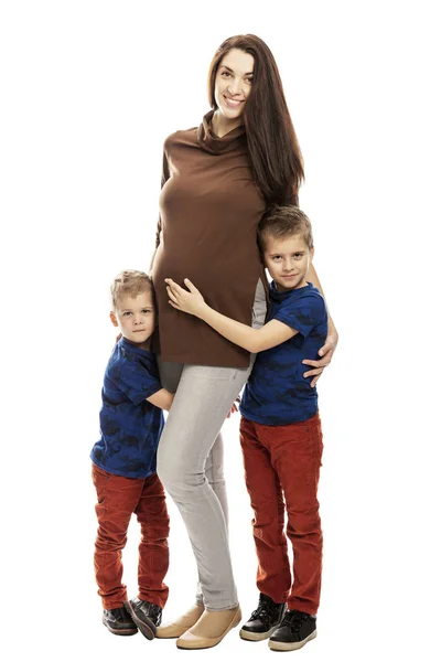 Pregnant mom and sons hug and smile, full height. Tenderness and love. Isolated on white background. — Stock Photo, Image
