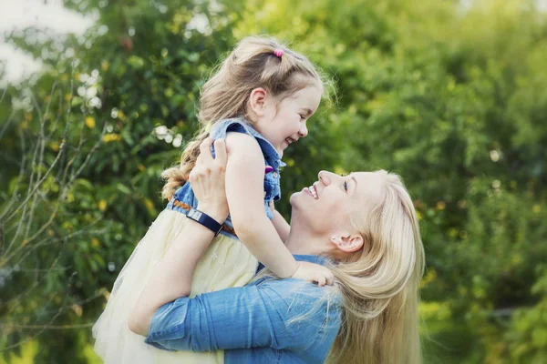 Mutter und Tochter lachen und umarmen sich im Sommer im Park. Zärtlichkeit und Liebe. — Stockfoto