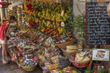 Taormina, İtalya, 08/30/2016: Eski kentte dar bir sokak. İnsanlar meyve ve hediyelik eşya satın alıyor..
