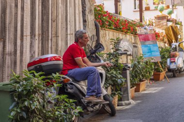 Taormina, İtalya, 08/30/2016: Bir adam gölgede bir scooter üzerinde oturuyor.