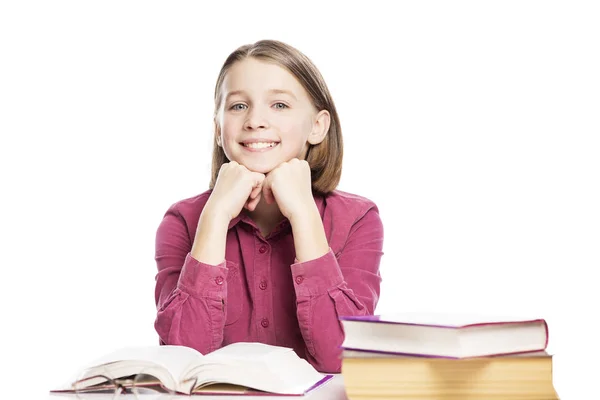 Χαμογελαστή έφηβη κοπέλα που κάθεται σε ένα τραπέζι με βιβλία. Απομονωμένη σε λευκό φόντο. — Φωτογραφία Αρχείου