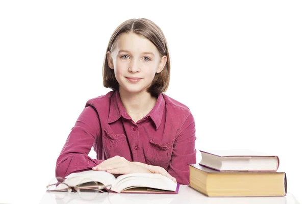 Glimlachend tiener meisje zittend aan een tafel met boeken. Geïsoleerd op een witte achtergrond. — Stockfoto