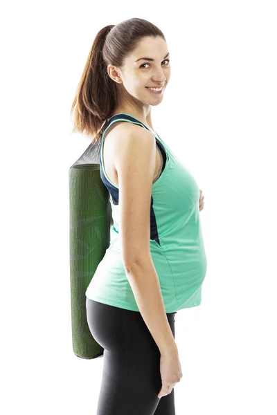 Pregnant woman with yoga mat on the shoulder. Isolated on a white background. — Stock Photo, Image