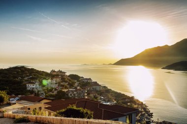 Gün batımı arka plan üzerinde deniz tarafından dağlarda rahat bir köy. Güneş patlaması. Güzel manzara.