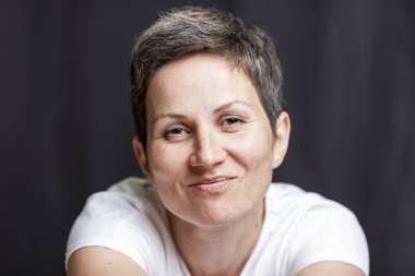 Kısa saçlı yetişkin bir kadının duygusal portresi. Close. Siyah arka plan.