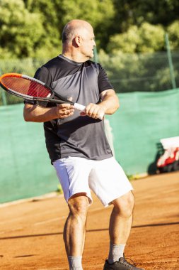 Orta yaşlı kel bir adam sahada duygusal olarak tenis oynar. Rakibi kaybeder. Açık. 