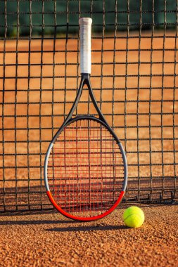 Toprak kortta filenin yanında topla tenis raket. Güneşli bir gün. Close.