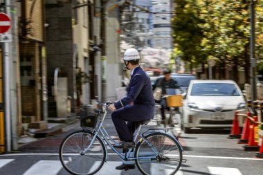 Tokyo, Japonya, 04/12/2019: Şehir caddesinde bisikletli kasklı bir adam.