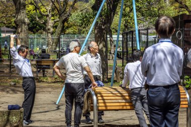 Tokyo, Japonya, 04/12/2019: Şehirdeki bir parkta spor egzersizleri yapan bir grup adam.