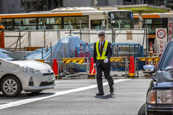 Tokyo, Japan, 04 / 12 / 2019: A man traffic controller on a city street . — стоковое фото