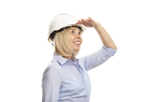 Mujer joven en ropa de oficina y un casco de construcción mira a la distancia. Primer plano. Fondo blanco . — Foto de Stock