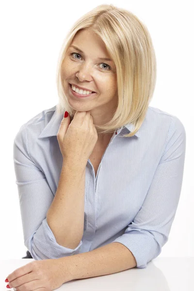 Lachende jonge vrouw in kantoor kleren zittend aan de tafel. Witte achtergrond, close-up. — Stockfoto