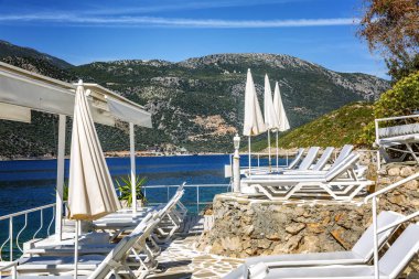 Güzel bir koyda beyaz şezlong ve şemsiye ile lüks plaj. Muhteşem manzara.