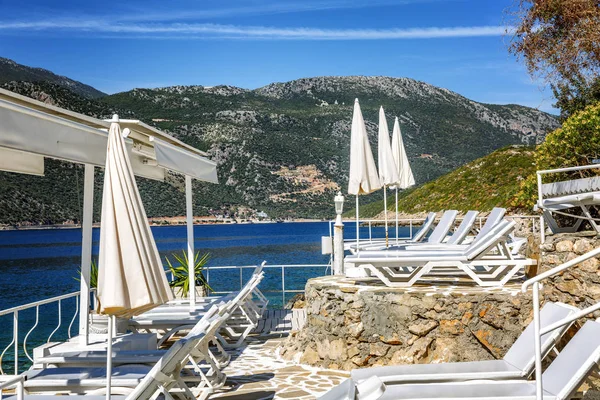 Güzel bir koyda beyaz şezlong ve şemsiye ile lüks plaj. Muhteşem manzara.