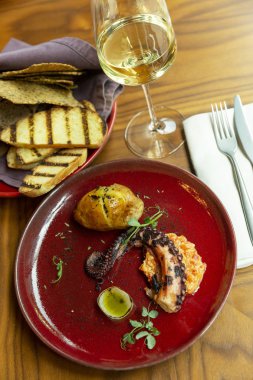 Restoranda kırmızı tabakta ızgara ahtapot. Beyaz şarap ile güzel dekore akşam yemeği.