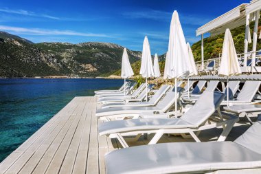 Beyaz şezlong ve şemsiyeile lüks plaj. Kalmak için harika bir yer.