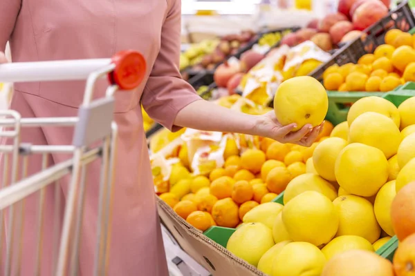 Uma jovem escolhe toranjas num supermercado. Close-up . — Fotografia de Stock