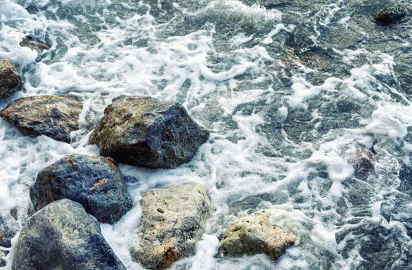 Αφρώδη κύματα στη θάλασσα σε μεγάλους βράχους στην ακτή. Γκρο πλαν. Φόντο. Χώρος για κείμενο. — Φωτογραφία Αρχείου