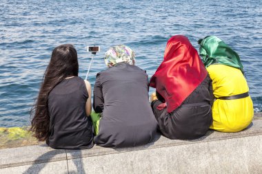 İstanbul, Türkiye, 07.25.2015: Parlak oryantal kıyafetler giyen kadınlar selfie çekiyor. Arka görüş. Müslüman ülke.