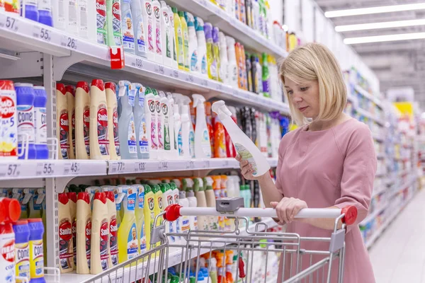 Москва, Россия, 07.24.2019: Молодая женщина в отделе бытовой химии в супермаркете выбирает продукт . — стоковое фото