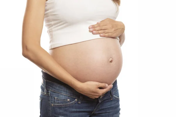 De zwangere vrouw raakt zachtjes haar grote buik. Wachten op een wonder. Close-up. Geïsoleerd op een witte achtergrond. — Stockfoto
